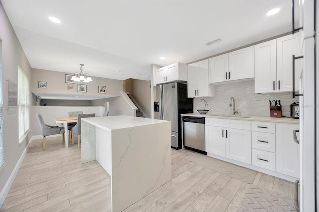 kitchen featuring visible vents, backsplash, appliances with stainless steel finishes, white cabinetry, and a sink