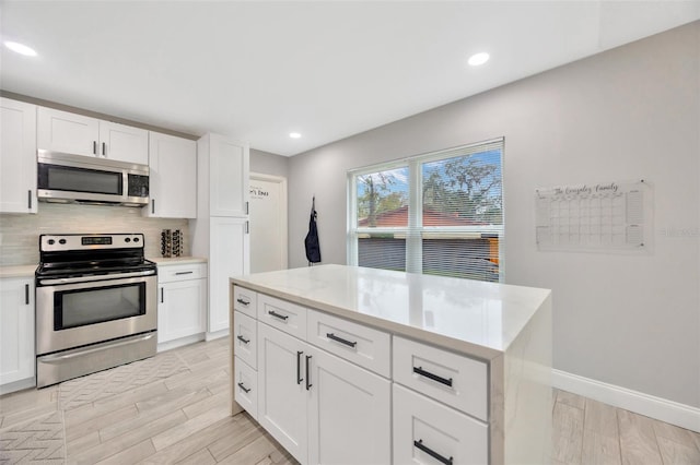 kitchen featuring light wood-style flooring, white cabinetry, stainless steel appliances, and decorative backsplash