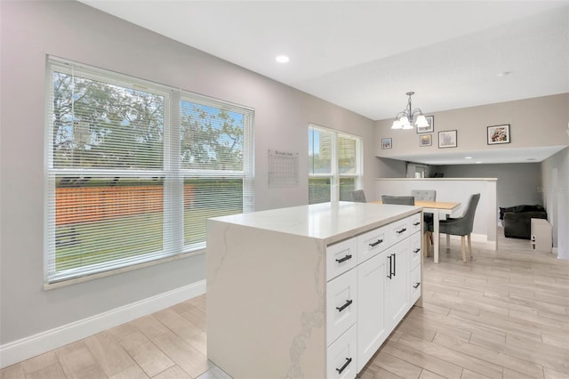 kitchen featuring light wood-type flooring, an inviting chandelier, white cabinetry, and hanging light fixtures