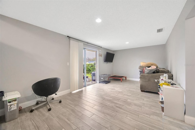 interior space with a textured ceiling, recessed lighting, visible vents, baseboards, and light wood-style floors