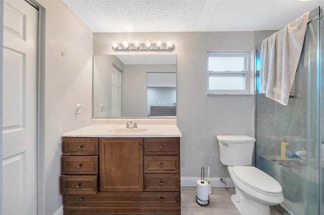 full bathroom with a stall shower, baseboards, toilet, a textured ceiling, and vanity