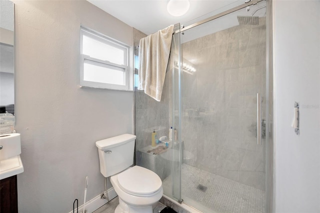 bathroom featuring toilet, a shower stall, vanity, and baseboards