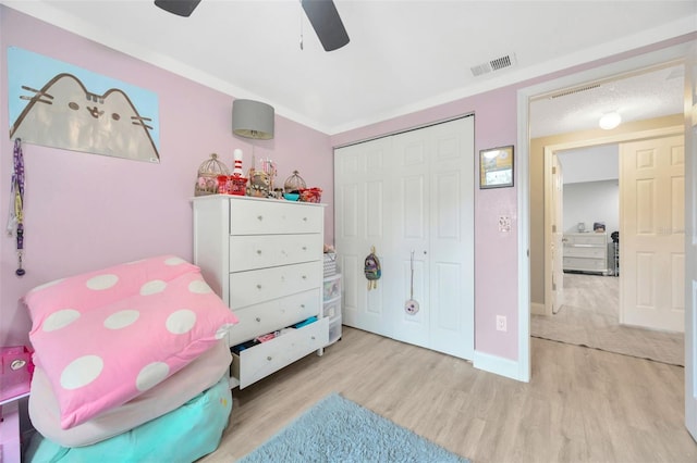 bedroom with ceiling fan, a closet, wood finished floors, and visible vents