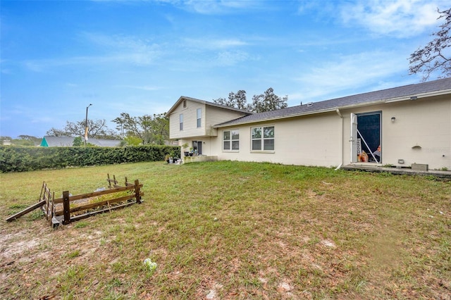 back of house with concrete block siding and a yard