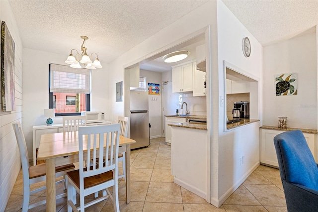 kitchen with white microwave, light tile patterned flooring, white cabinets, and freestanding refrigerator