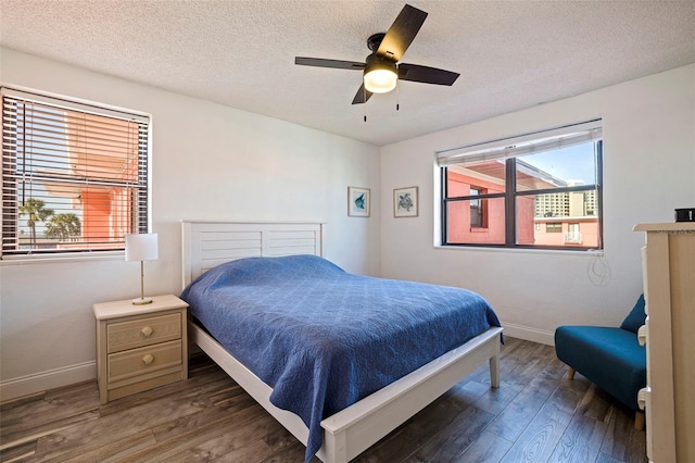 bedroom with a textured ceiling, multiple windows, wood finished floors, and baseboards