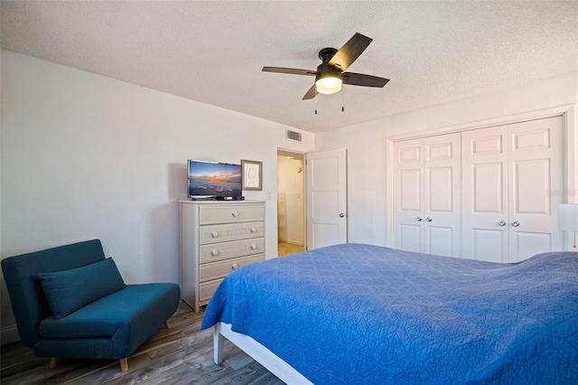 bedroom featuring ceiling fan, a textured ceiling, visible vents, and wood finished floors