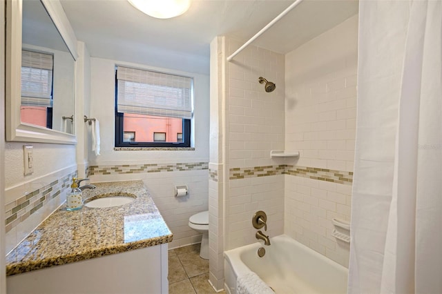 full bathroom featuring toilet, tile patterned flooring, shower / bath combo with shower curtain, vanity, and tile walls