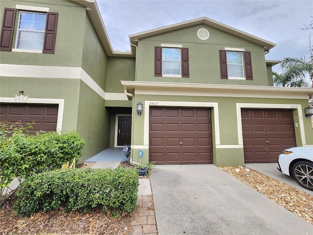 view of front facade with concrete driveway, an attached garage, and stucco siding