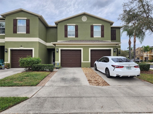 view of front of home with driveway, an attached garage, and stucco siding