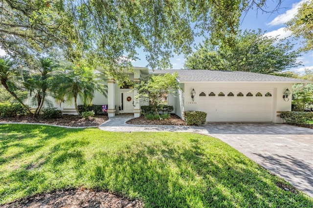 view of front of home with a garage, decorative driveway, a front lawn, and stucco siding