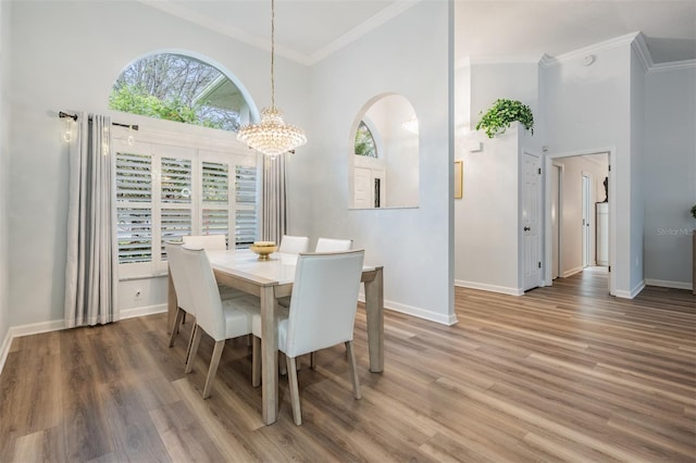 dining area featuring a high ceiling, ornamental molding, a chandelier, and dark wood finished floors