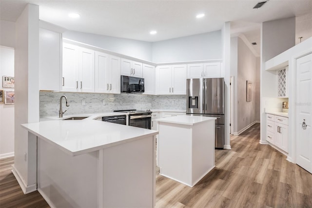 kitchen featuring a center island, light countertops, appliances with stainless steel finishes, white cabinetry, and a sink