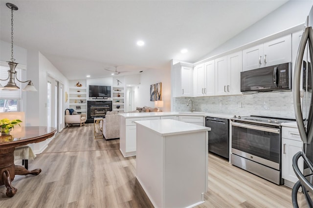 kitchen featuring a peninsula, open floor plan, light countertops, black appliances, and pendant lighting