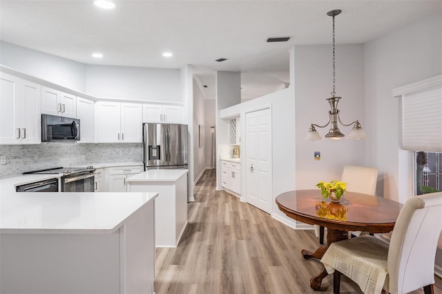 kitchen featuring white cabinets, stainless steel appliances, light countertops, and decorative light fixtures