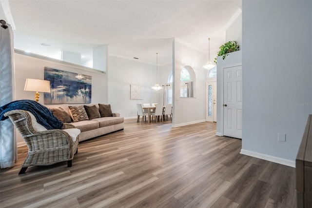 living room with baseboards, high vaulted ceiling, wood finished floors, and crown molding