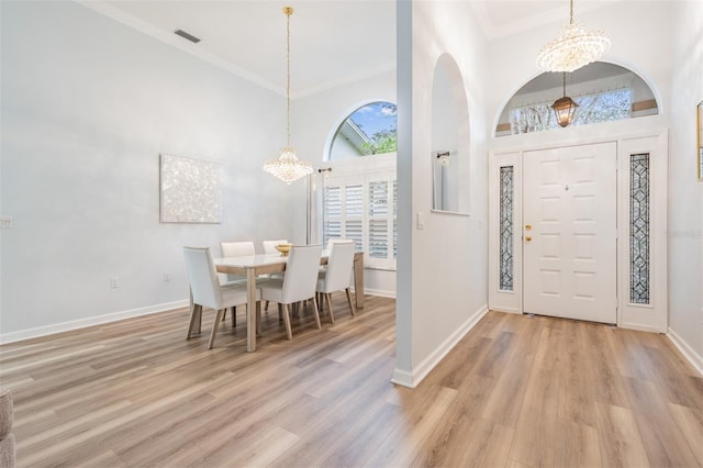 entrance foyer featuring light wood finished floors, crown molding, and a notable chandelier