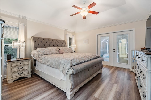 bedroom featuring french doors, a raised ceiling, ornamental molding, wood finished floors, and access to outside