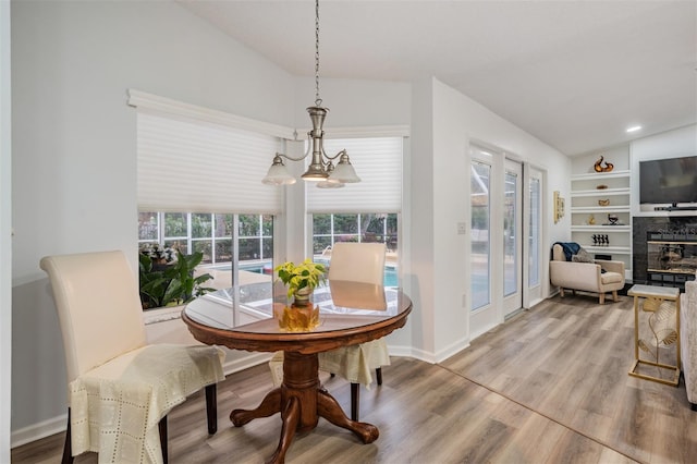 dining room with vaulted ceiling, a tiled fireplace, wood finished floors, and baseboards