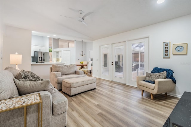 living area featuring light wood-style floors, lofted ceiling, baseboards, and a ceiling fan