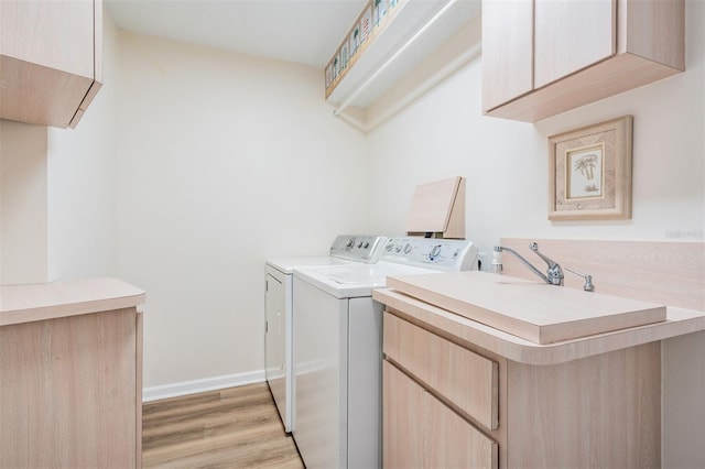 laundry area with light wood-type flooring, cabinet space, baseboards, and independent washer and dryer