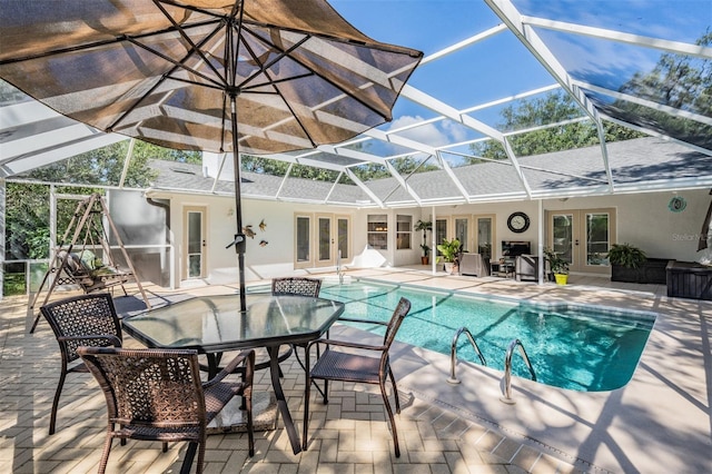 pool with a lanai, a patio area, and french doors