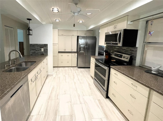 kitchen featuring appliances with stainless steel finishes, a sink, decorative backsplash, and dark stone countertops