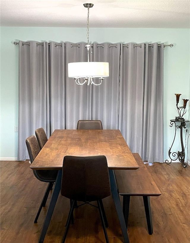 dining area featuring a notable chandelier, a textured ceiling, baseboards, and wood finished floors