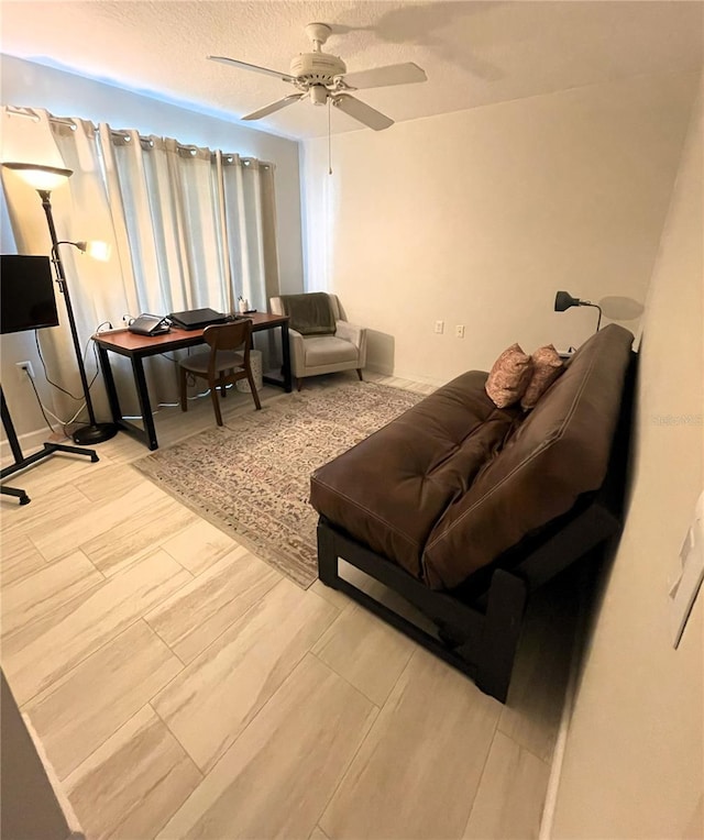 living area featuring a ceiling fan, a textured ceiling, and wood finished floors