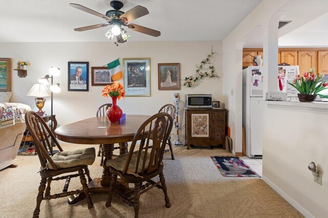 dining room featuring light carpet, ceiling fan, and baseboards