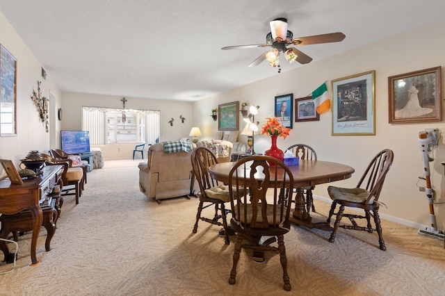 dining room featuring light carpet, visible vents, baseboards, and ceiling fan