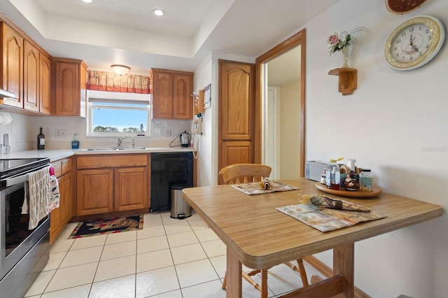 kitchen with black dishwasher, tasteful backsplash, brown cabinetry, stainless steel range with electric cooktop, and a sink