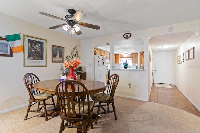 dining area featuring light colored carpet, ceiling fan, a textured ceiling, and baseboards