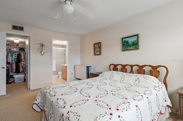 bedroom with light carpet, visible vents, a spacious closet, a closet, and ensuite bath