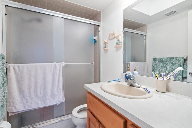 bathroom featuring toilet, a skylight, vanity, visible vents, and a shower stall