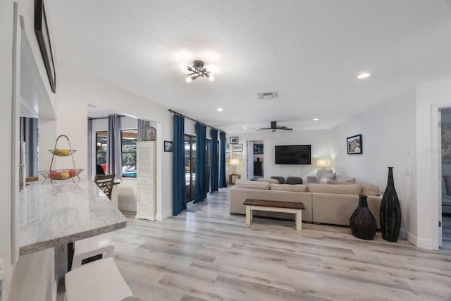 living room featuring a textured ceiling, light wood finished floors, a ceiling fan, and recessed lighting