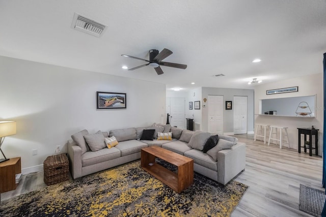 living room with recessed lighting, a ceiling fan, visible vents, baseboards, and light wood-type flooring