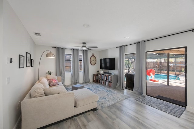 living area featuring ceiling fan, a sunroom, wood finished floors, and visible vents