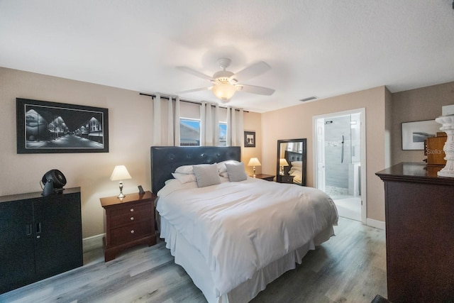 bedroom with visible vents, a ceiling fan, ensuite bath, wood finished floors, and baseboards