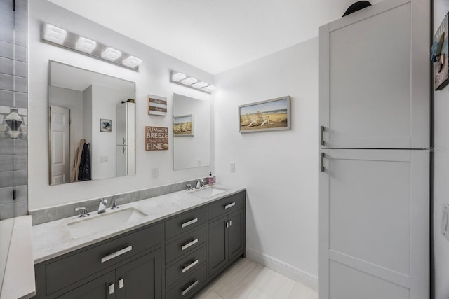 full bathroom featuring double vanity, baseboards, and a sink