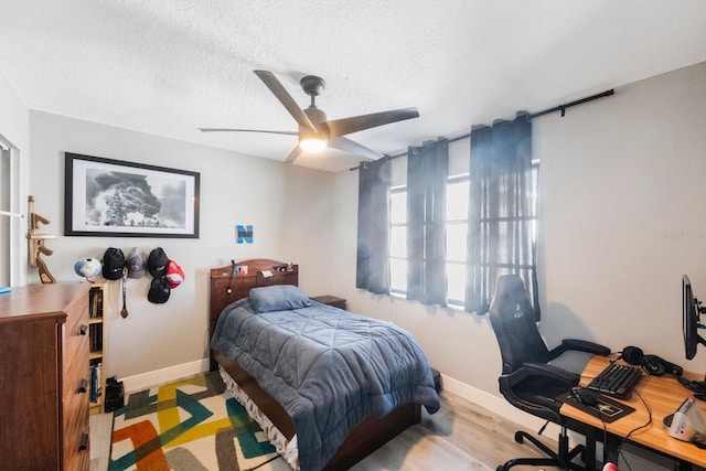 bedroom with ceiling fan, a textured ceiling, baseboards, and wood finished floors