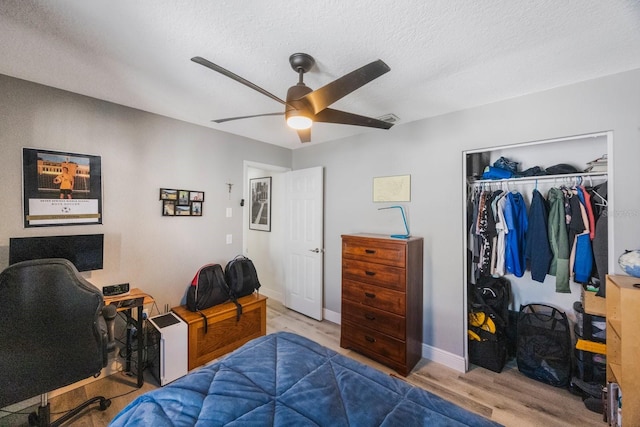 bedroom featuring a textured ceiling, a closet, wood finished floors, and a ceiling fan