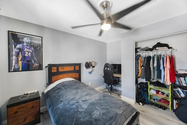 bedroom featuring baseboards, ceiling fan, wood finished floors, a textured ceiling, and a closet