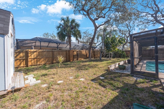 view of yard with a lanai, a fenced backyard, and a fenced in pool