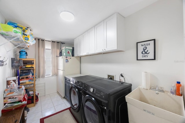 washroom featuring light tile patterned floors, washing machine and clothes dryer, a sink, and cabinet space