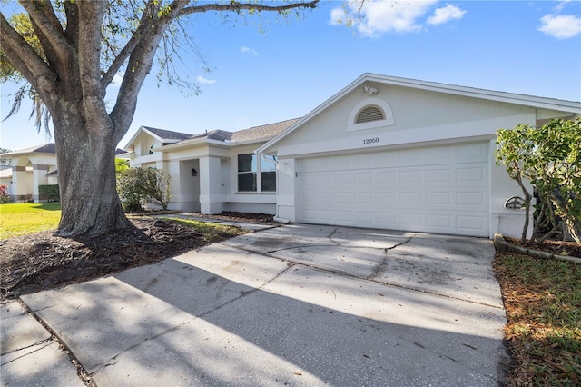 ranch-style house featuring a garage, concrete driveway, and stucco siding