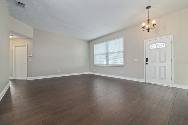 foyer featuring visible vents, baseboards, dark wood-type flooring, and a chandelier