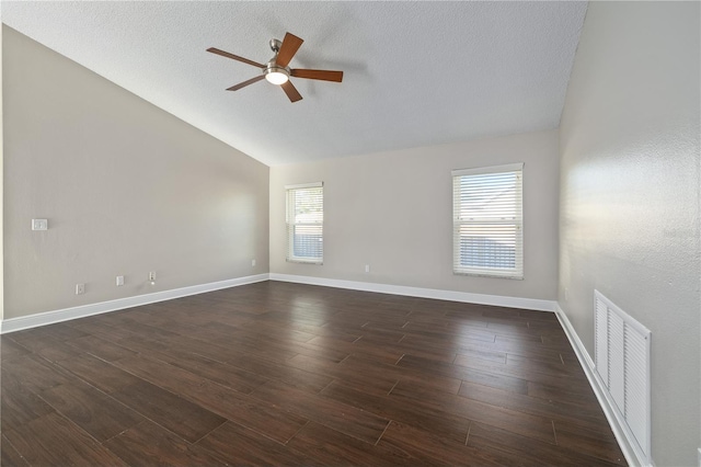 unfurnished room with visible vents, dark wood-type flooring, baseboards, vaulted ceiling, and a textured ceiling