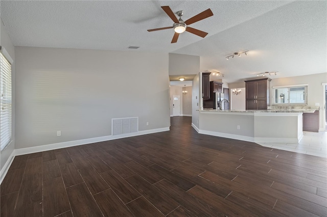 unfurnished living room featuring wood finish floors, visible vents, baseboards, and a textured ceiling