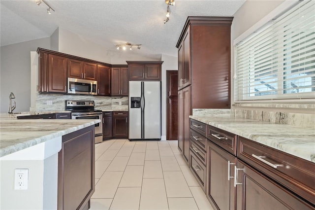 kitchen with lofted ceiling, light stone counters, tasteful backsplash, and stainless steel appliances